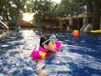 Boy wearing water wings swimming in pool at yard