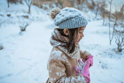 Rear view of woman standing on snow covered field