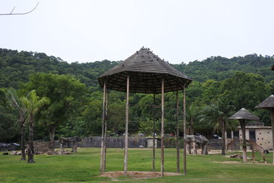 House on field by trees against clear sky