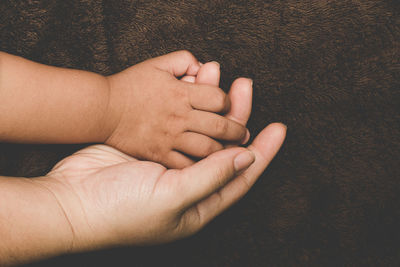 Cropped hands of child and parent on blanket 