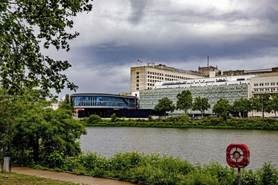 Bridge over river by buildings against sky