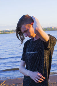 Young man looking down at beach against sky