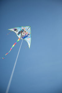 Low angle view of kites flying against clear blue sky