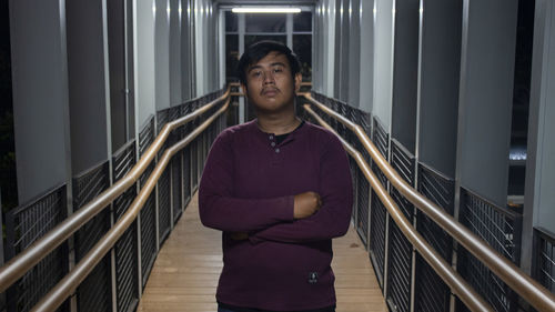 Portrait of young woman standing against railing