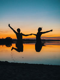 Silhouette people on beach against sky during sunset