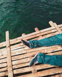 Low section of man relaxing on wooden raft