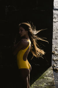 Low key portrait of beautiful latin woman in yellow swimsuit