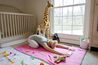 A woman stretching in yoga child's pose in daughters room with crib