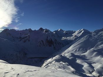 Scenic view of snowcapped mountains against blue sky