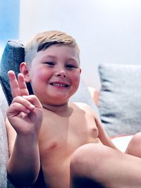 Portrait of smiling boy sitting on sofa at home