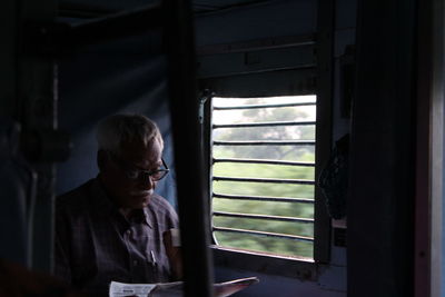 Senior man reading newspaper while traveling in train