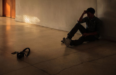 Depressed man silhouette man sitting against wall