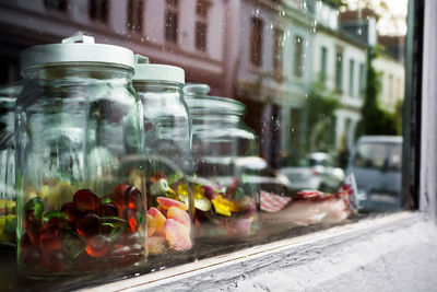 Close-up of candies in glass jars seen from store window