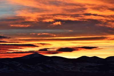 Scenic view of silhouette mountains against orange sky