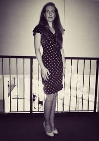 Portrait of woman standing against railing