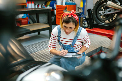 Mechanic reviewing damages in motorbike on garage