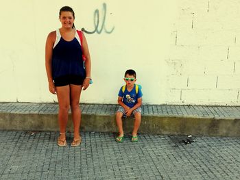 Portrait of siblings against wall