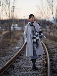 A lady standing on the railroad tracks