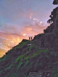 People on cliff against sky during sunset