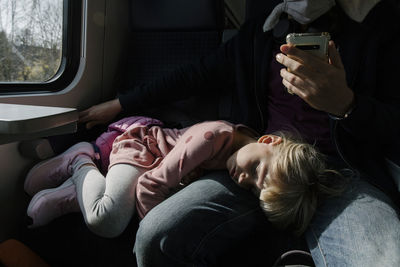 Girl sleeping on father's lap in train