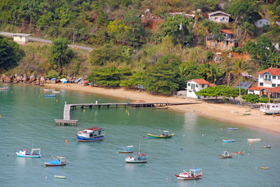 High angle view of sailboats moored on sea by buildings