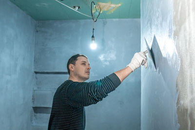 Portrait of young man standing against wall