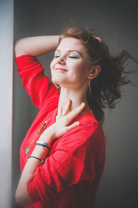 Portrait of young woman standing against wall