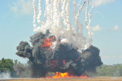 Fire and smoke over field against sky