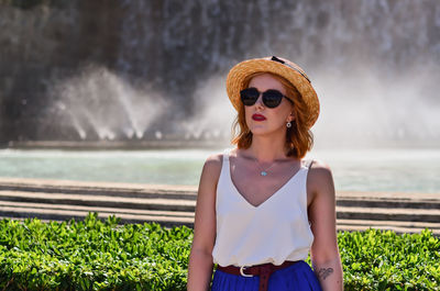 Young woman wearing sunglasses standing pond