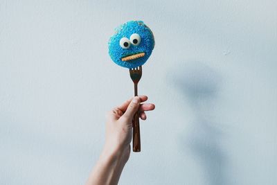 Cropped image of hand holding cookie against wall