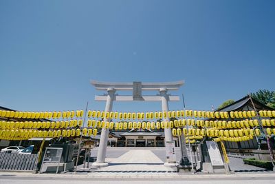 Yellow lanterns at entrance on temple against clear blue sky