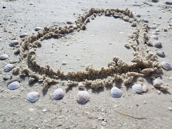 Close-up of heart shape on sand at beach