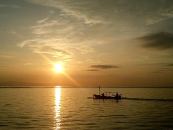 Silhouette people on boat in sea against sky during sunset