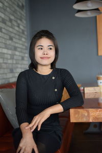 Thoughtful young woman looking away while sitting in cafe