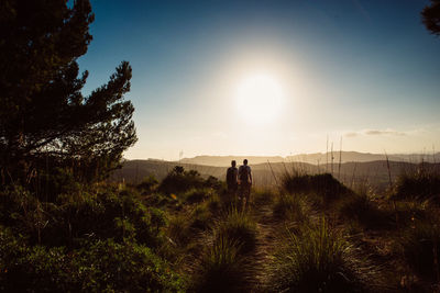 Rear view of man walking on field against sky
