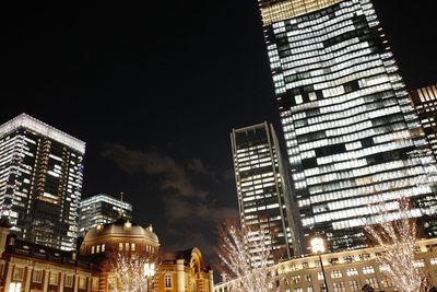 Low angle view of illuminated buildings against sky at night