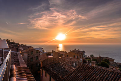 Buildings by sea against sky during sunset