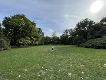 People walking on grassy field against sky