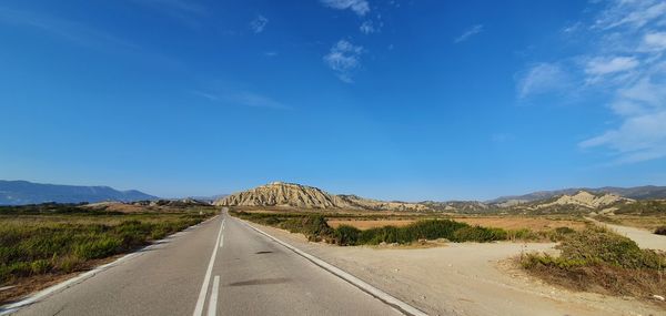 Road leading towards mountains against sky