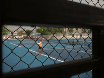 Chainlink fence against sky seen through window