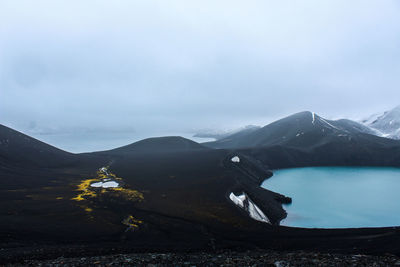 Scenic view of lake by mountains against sky