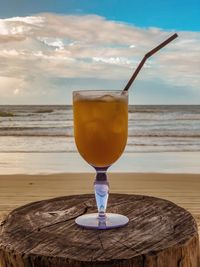 Close-up of drink on table at beach against sky