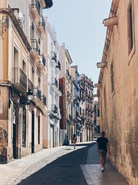 Rear view of man walking on street in city