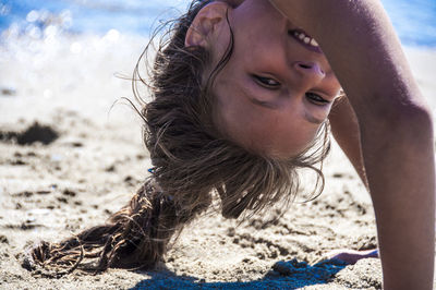 Portrait of girl performing handstand at beach on sunny day