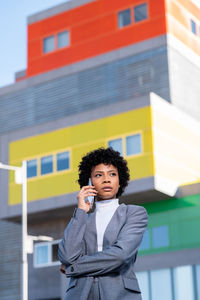 Portrait of young woman standing against building