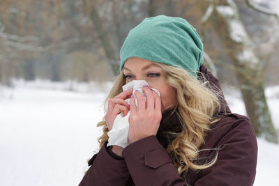 Portrait of blond woman blowing nose in park