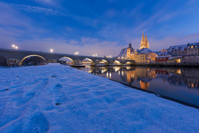 Illuminated bridge over river against sky during winter