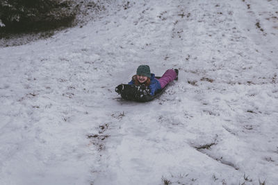 Full length of girl sitting on bobsled in snow