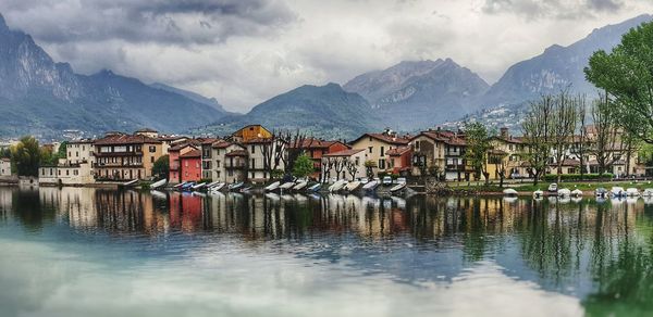 Houses by lake and mountains against sky