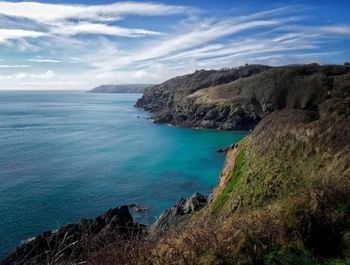 Scenic view of sea by cliff against sky